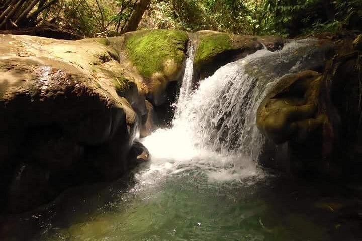 A small cascade running over moss-covered limestone into a river pool