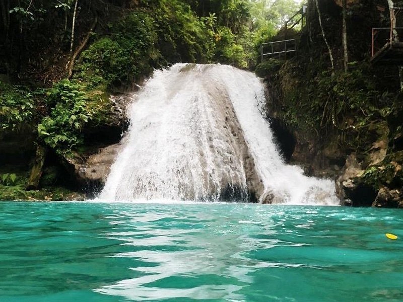 A waterfall spilling into a clear turquoise pool ringed by jungle